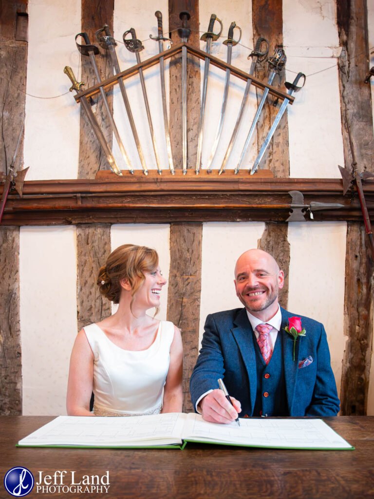 Bride and Groom signing the wedding registrar in the Lord Leycester Hospital in Warwick