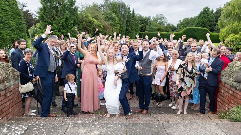 A joyful group of wedding guests and newlyweds celebrating outdoors, captured by a talented Wedding Photographer in Stratford Upon Avon, Warwickshire.